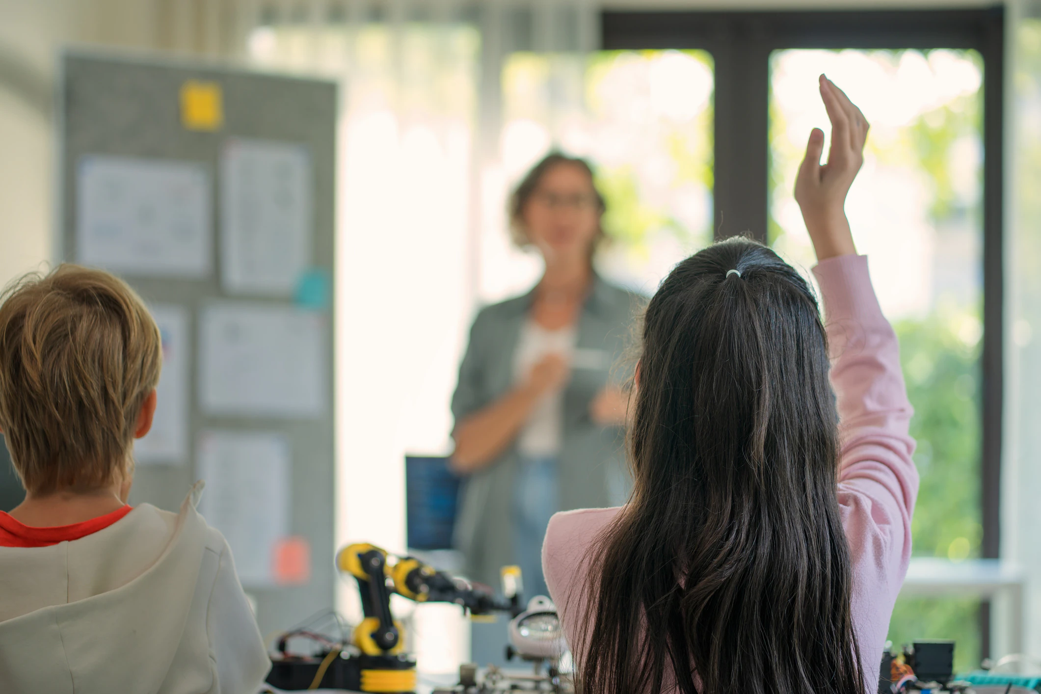 Ein Mädchen in der Grundschule hebt die Hand.